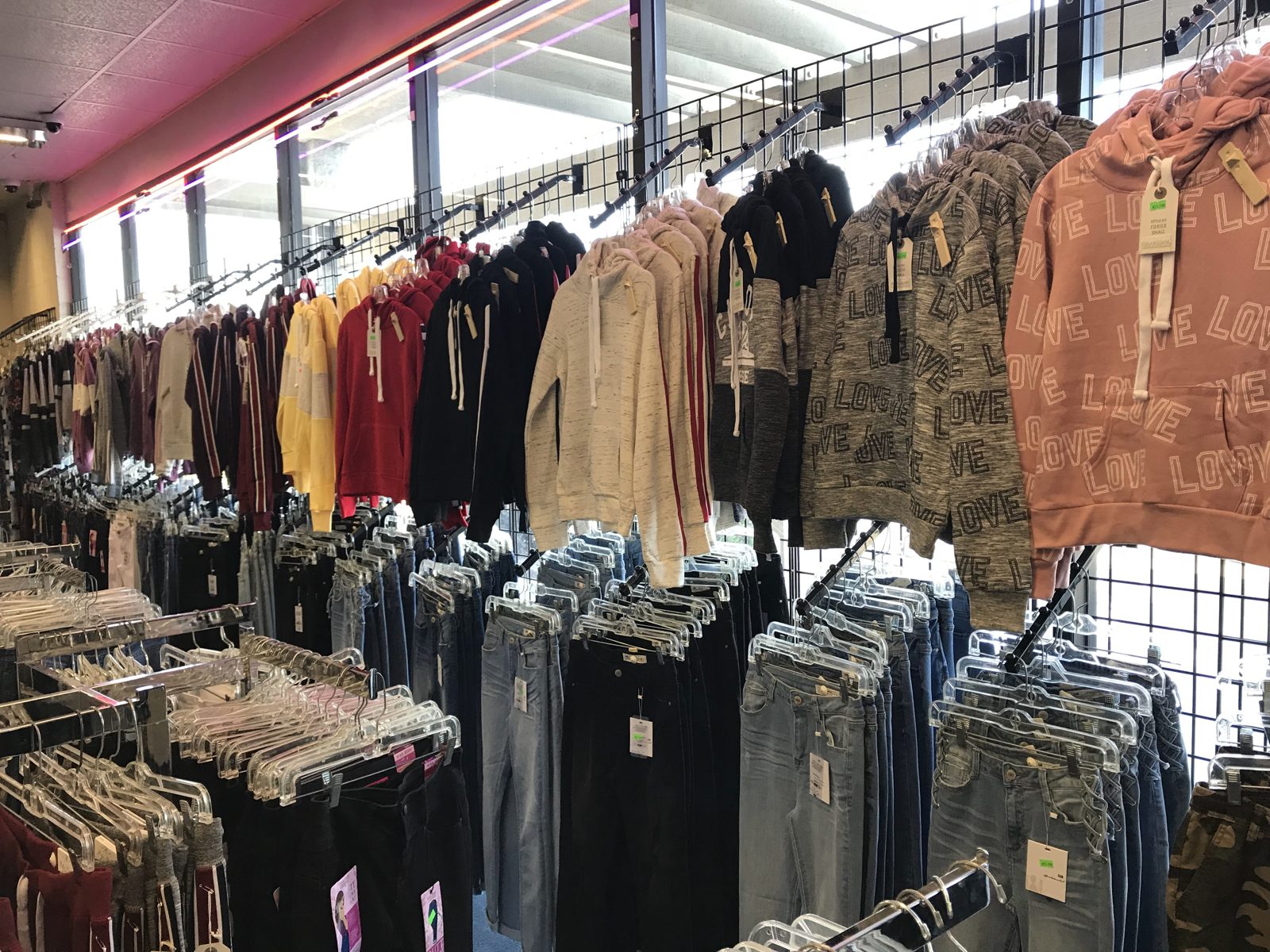 Wall of hanging hoodies above racks of jeans and pants